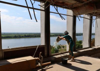 Працівниця бібліотеки викидає залишки битого скла через і сміття через розбиті вікна